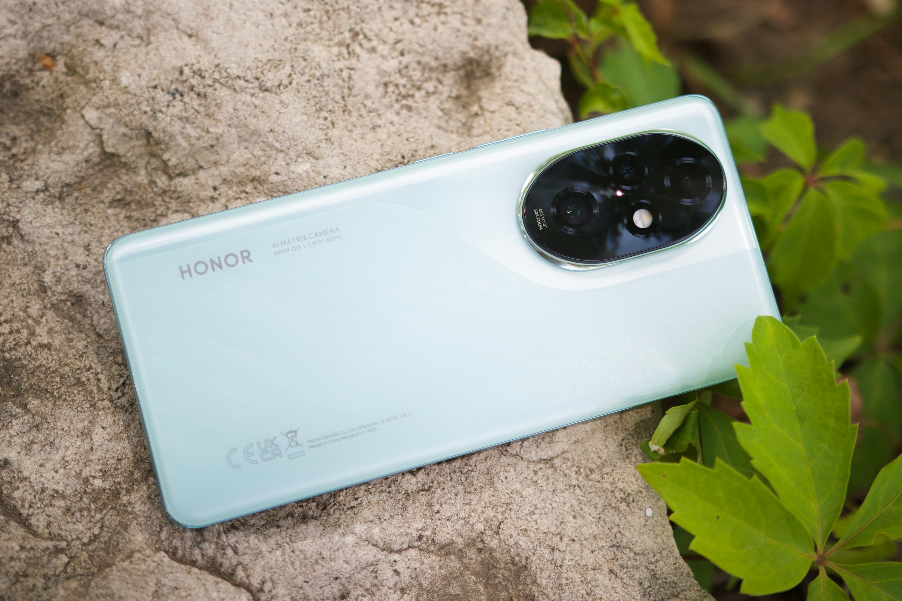 The Honor 200 Pro smartphone lying on a rock outside.