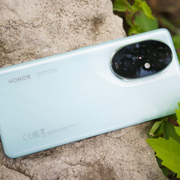 The Honor 200 Pro smartphone lying on a rock outside.