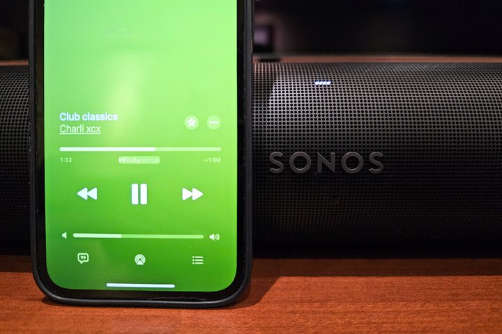 An iPhone playing Dolby Atmos Music from Apple Music sitting in front of a Sonos Arc soundbar.