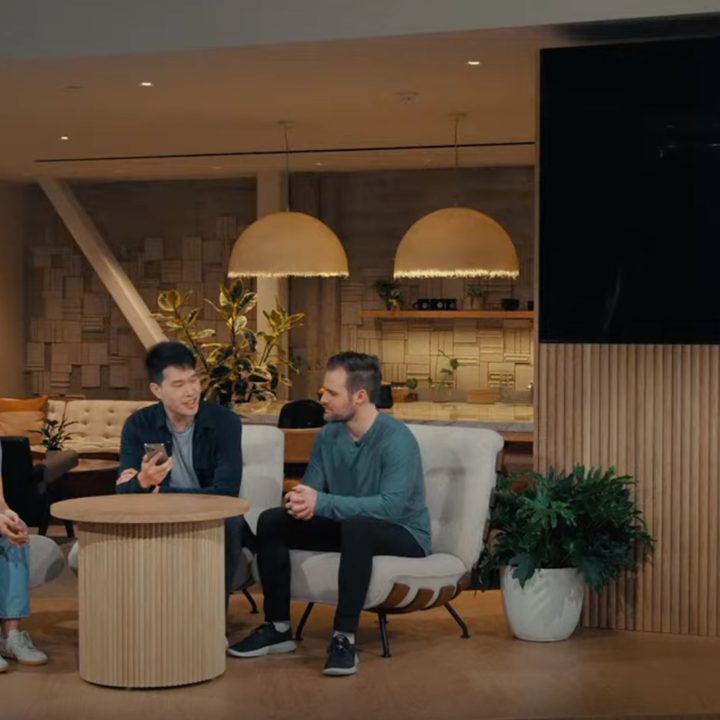 A screenshot from the OpenAI Spring Update showing three representatives on stage against a screen.