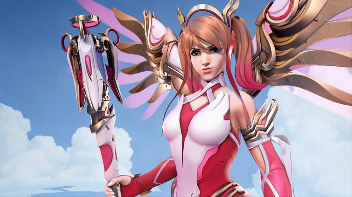 Mercy in her rose gold outfit. Her hair is strawberry blonde with pink tips and her outfit is different shades of pink.