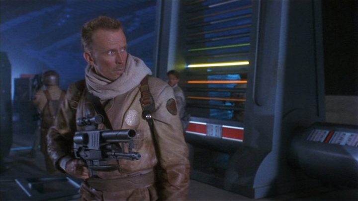 A man holding a gun and looking to the right in a scene from Screamers.