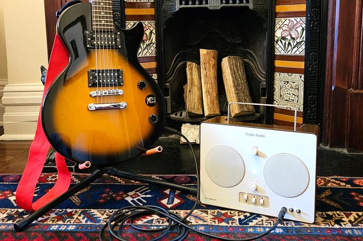 An electric guitar plugged into a Tivoli Audio SongBook.