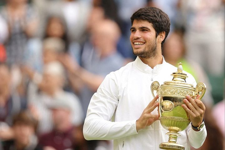 Carlos Alcaraz holds a trophy at Wimbledon.