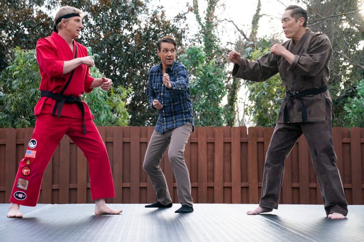 Two men square up in karate while one man refs.