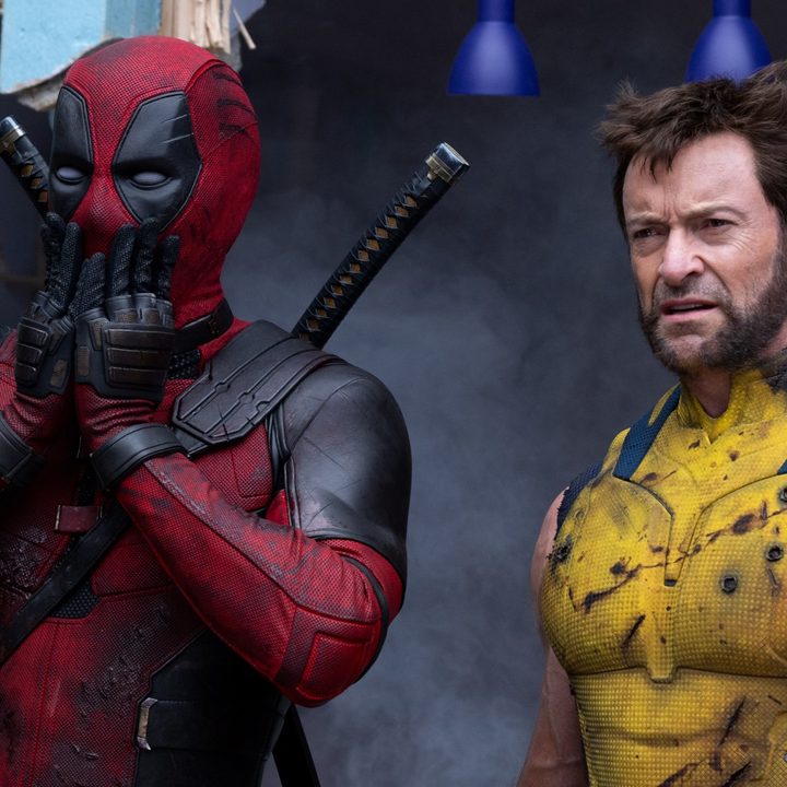 A masked Ryan Reynolds covers his mouth as Hugh Jackman glowers in a still from the movie "Deadpool & Wolverine."