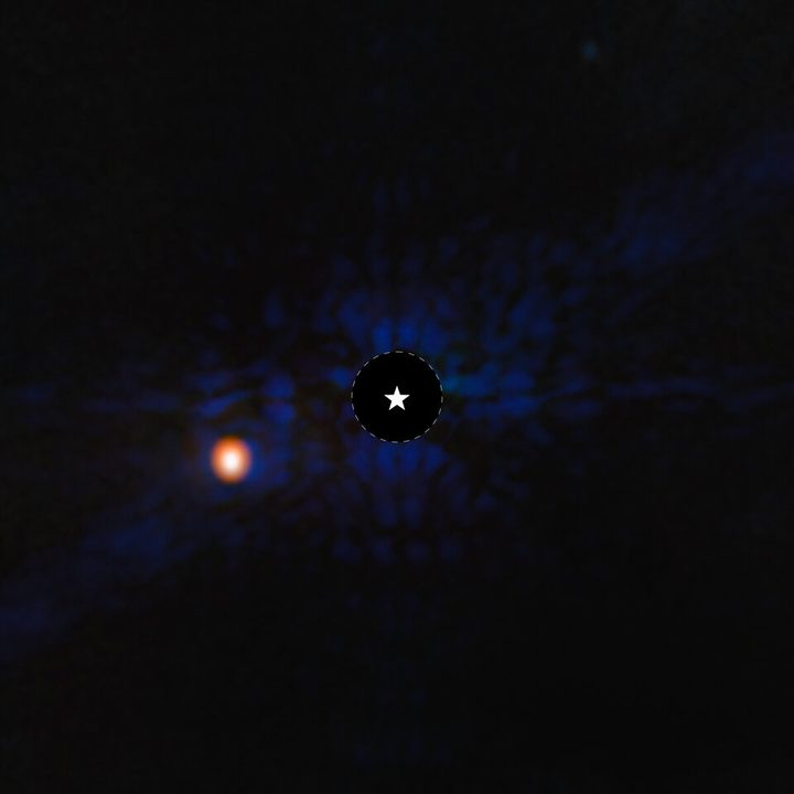 The gas-giant exoplanet Epsilon Indi Ab imaged using the MIRI instrument on NASA’s Webb telescope. A star symbol marks the location of the host star, whose light has been blocked by MIRI’s coronagraph, resulting in the dark circle with a dashed white line. The planet is to the left of the star.