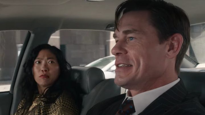 A woman with a bloody nose sits in the front seat of a car and looks at a man driving.