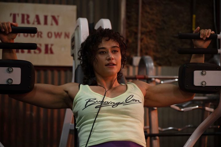 Katy O'Brian wears headphones while working out in Love Lies Bleeding.