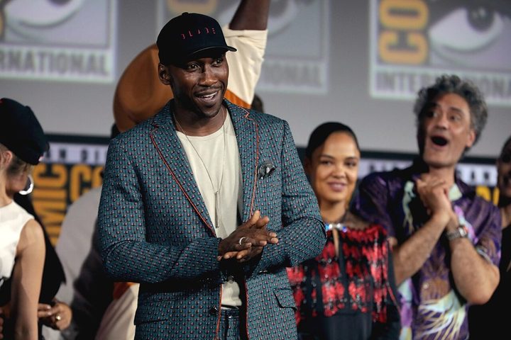 A man clasps his hands together whil looking into a crowd.