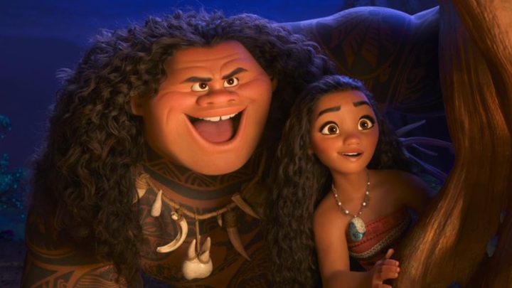 Maui and Moana stand next to each other and stare.