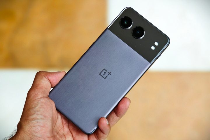 OnePlus Nord 4 held in hand against yellow and white background.