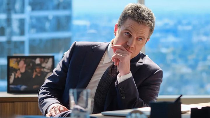 A man sits at a desk and ponders.