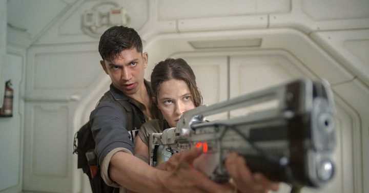 A man helps a woman point a gun in Alien: Romulus.