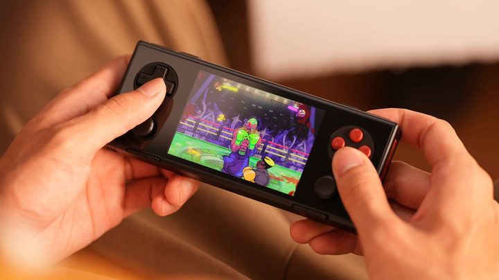 An Ayaneo Pocket Micro in black. It's being held by a person and looks like a small black square with buttons and a d-pad.