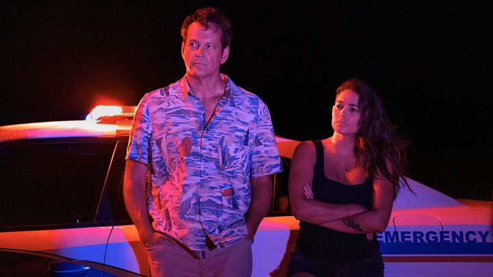 Vince Vaughn and a woman stand by a car in the dark with lights on them in a scene from Bad Monkey.