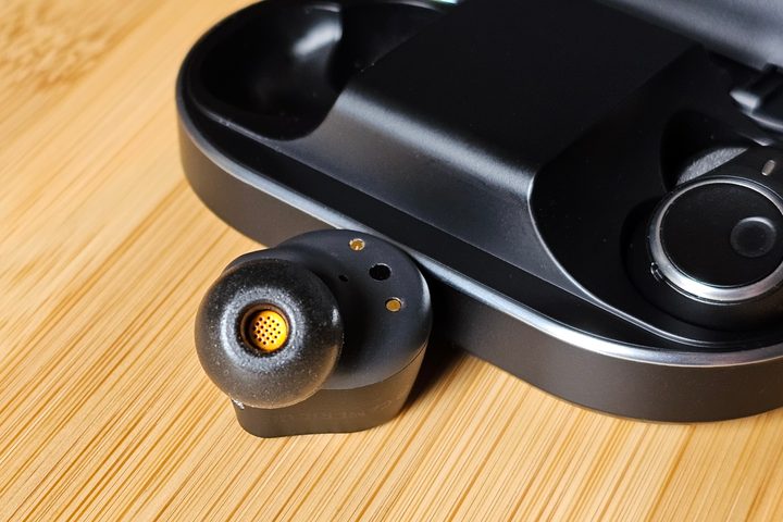 Cambridge Audio Melomania M100: one earbud in front of charging case.