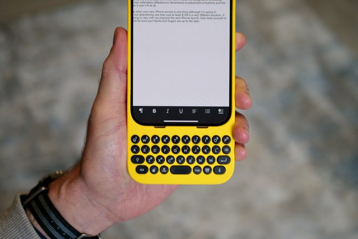 A person holding the iPhone 15 Pro Max inside the Clicks Keyboard case.
