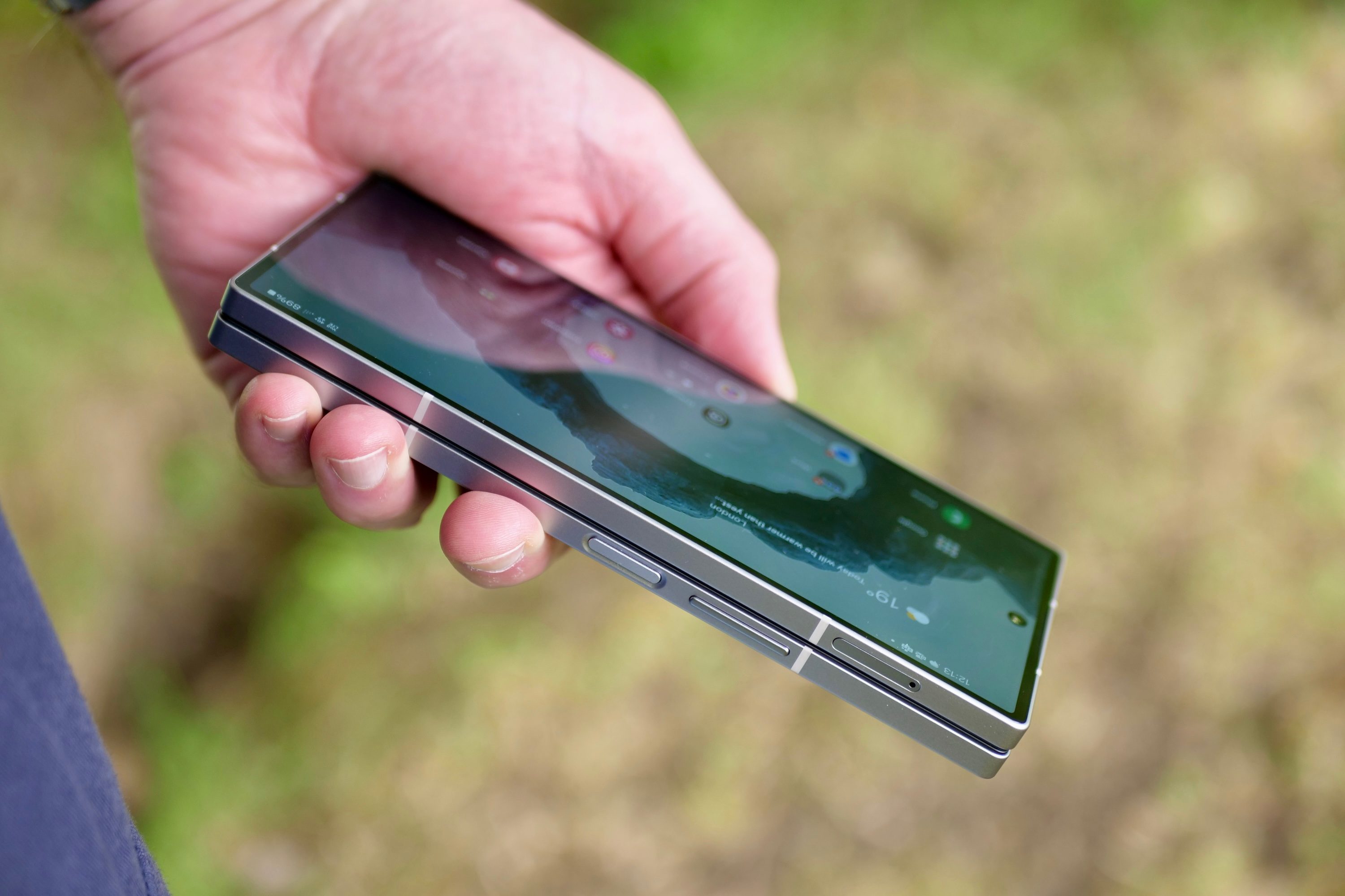 A person holding a closed Samsung Galaxy Z Fold 6, showing the buttons.