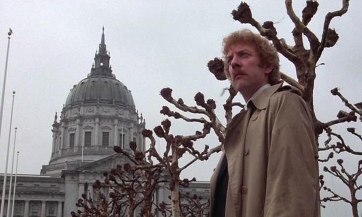 A man stands near bare trees in Invasion of the Body Snatchers.