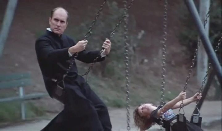 A priest and a child swing on a playground in Invasion of the Body Snatchers.