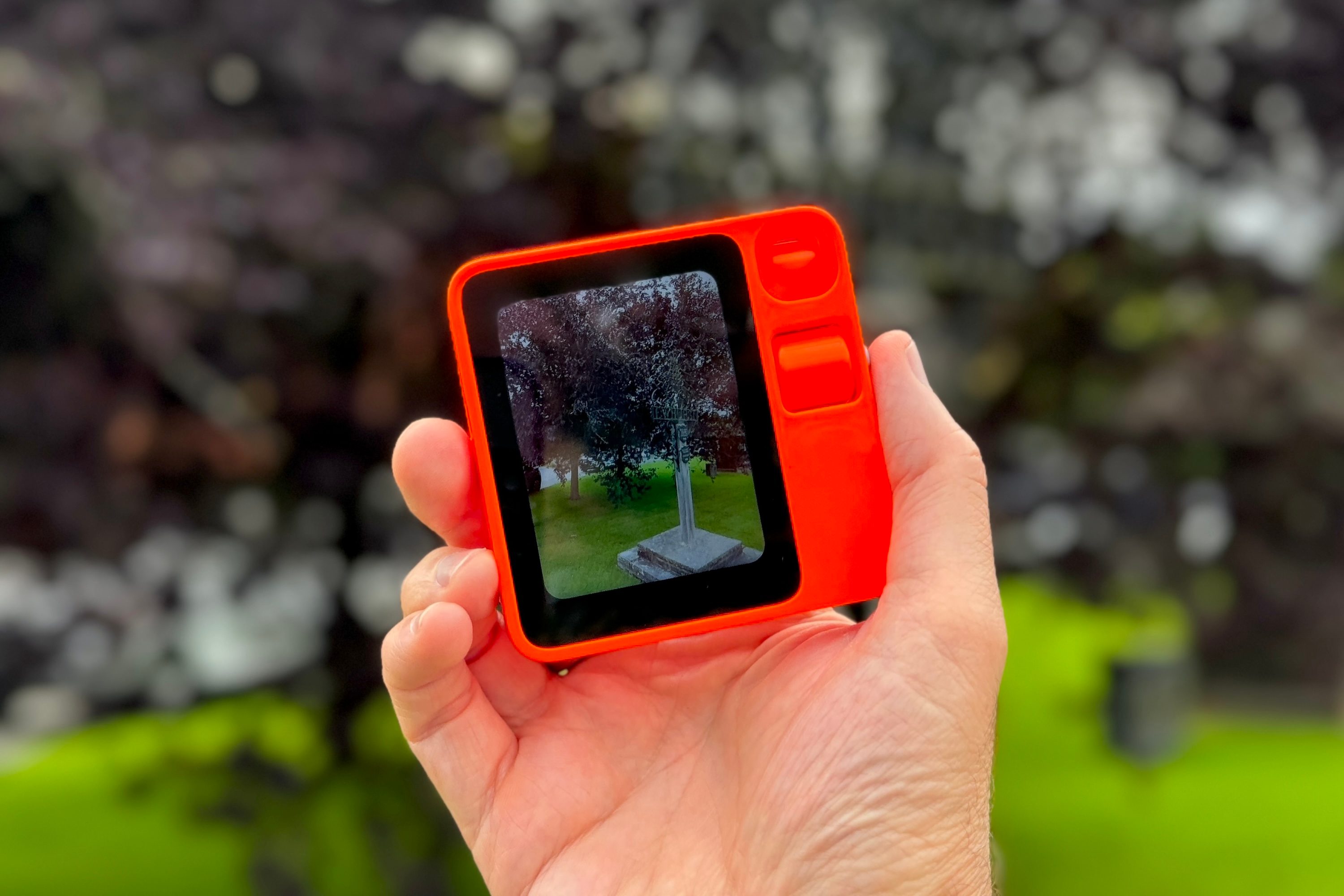 A person holding the Rabbit R1 and taking a photo.