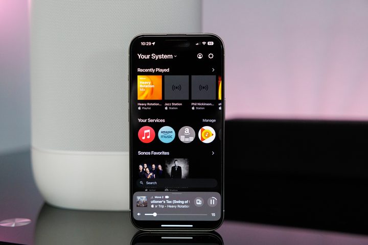 Sonos app on iPhone in front of a Sonos Move 2 speaker.
