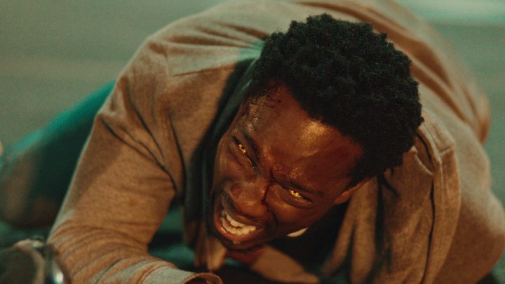 A man lying on the ground growling with lit eyes in Supacell on Netflix.
