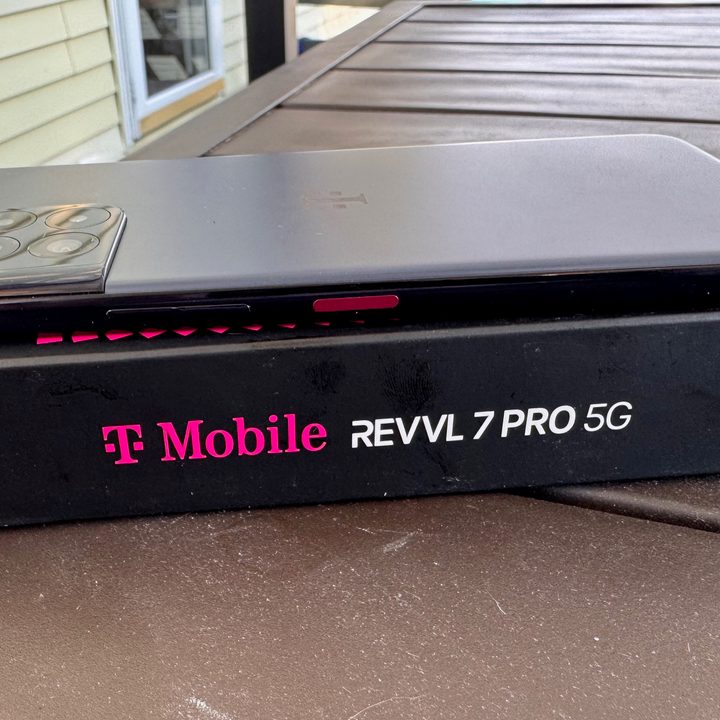 The T-Mobile REVVL 7Pro 5G phone lies face down on top of its box.