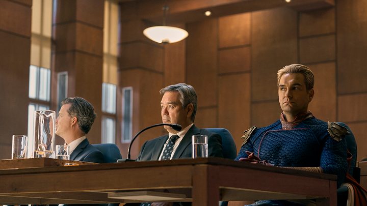 Homelander sitting at a table with two politicians on The Boys.