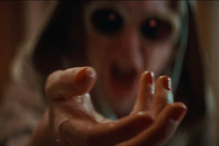 A screeching hooded woman holds up a slimy hand in Cuckoo.