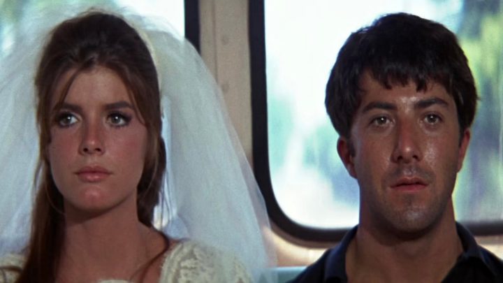 A man and woman sit next to each other on the bus and stare.