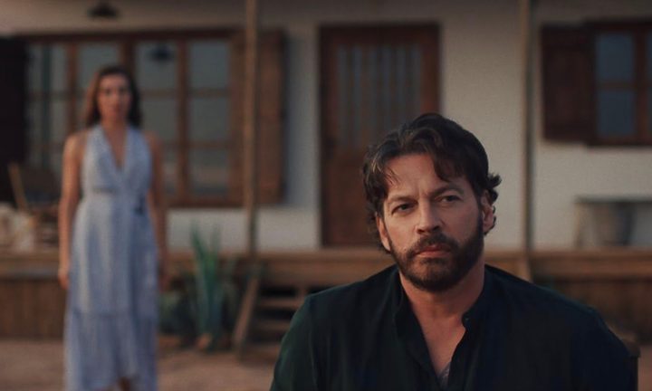 Harry Connick Jr. stares while a woman walks behind him.