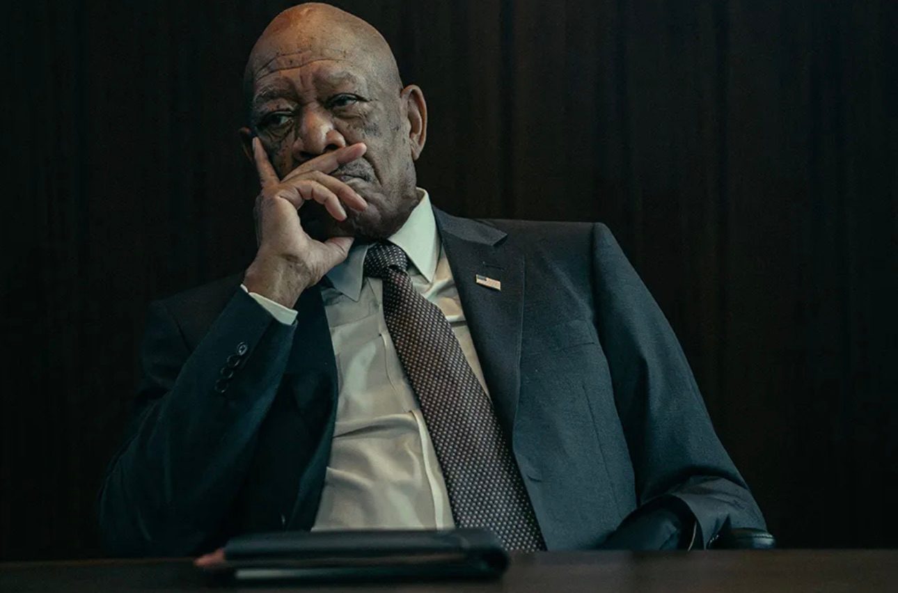 Morgan Freeman sits down and puts his hand on his face.