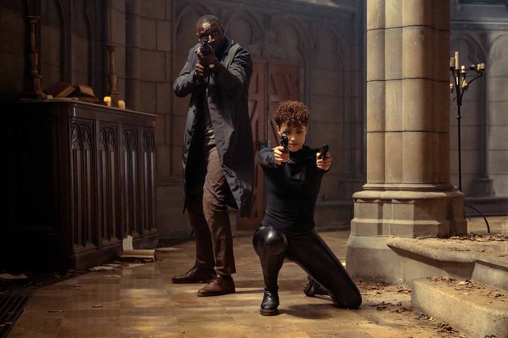 Omar Sy and Nathalie Emmanuel pose with guns in a church in The Killer.