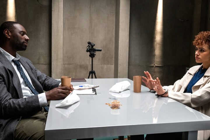 Omar Sy and Nathalie Emmanuel sit across a table from each other in The Killer.