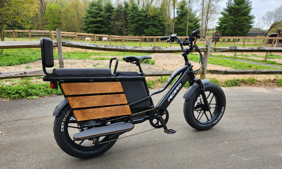 Pedego Cargo right profile parked on asphalt on a farm with fences, barns, and livestock.