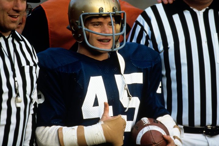 A football player puts a thumbs up and smiles.