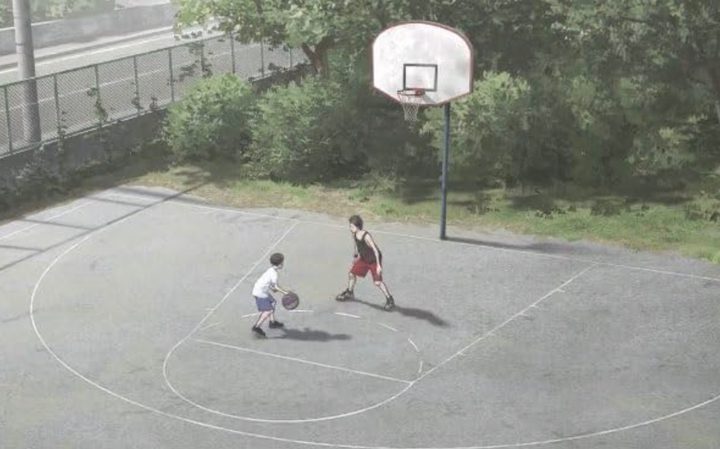 Two boys play basketball on an outdoor court.