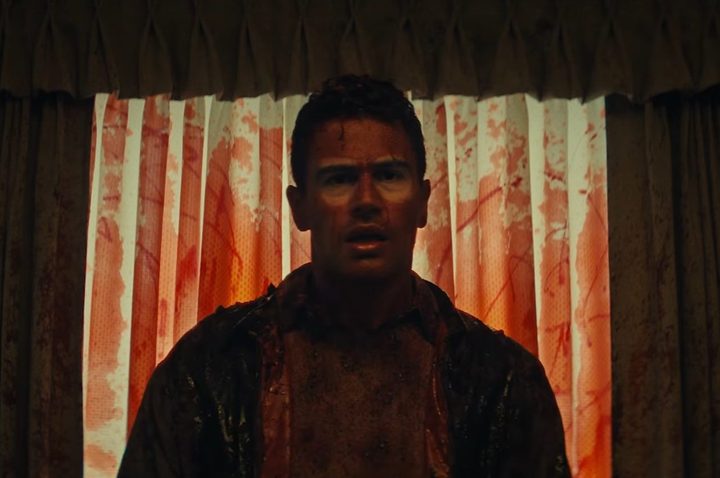 A bloody Theo James stares with a confused look on his face.