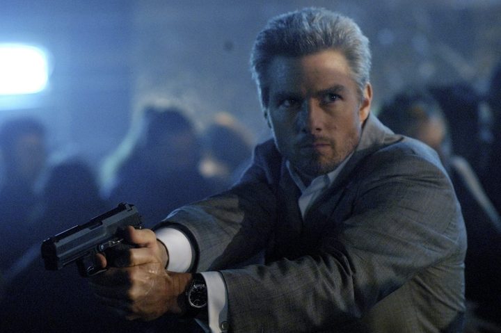 Tom Cruise holds and points a gun.
