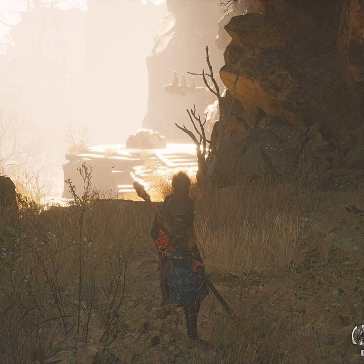The image shows the player looking at a statue head on a cliff's edge.