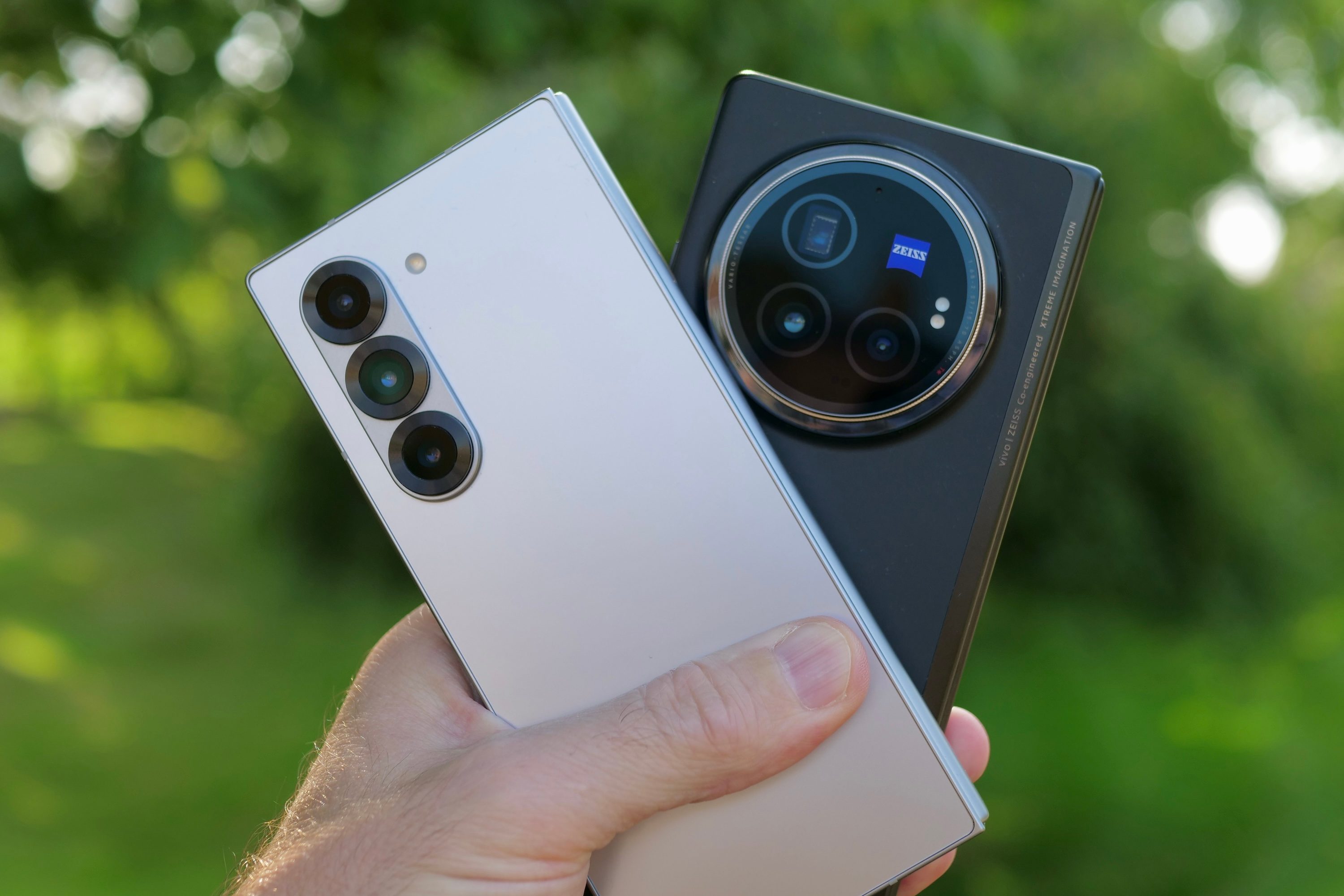 A person holding the Samsung Galaxy Z Fold 6 and Vivo X Fold3 Pro.