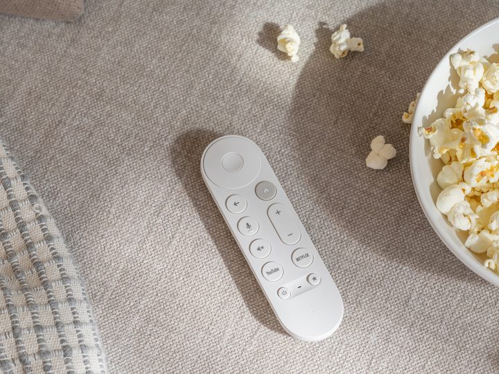A promo image of the Google TV Streamer remote alongside a bowl of popcorn.
