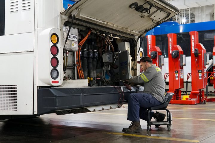 A man repairing an electric bus.