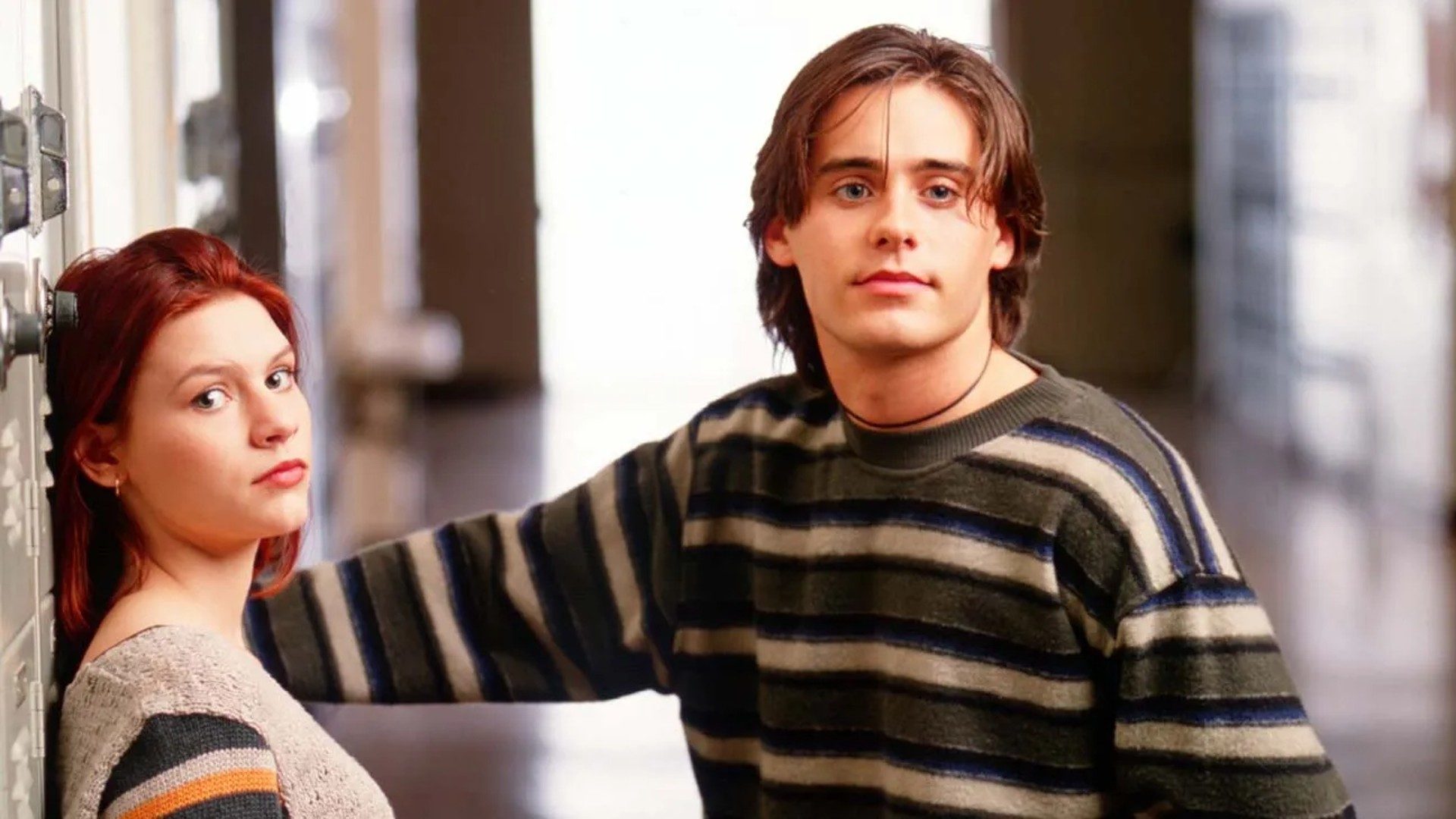Claire Danes and Jared Leto stand in a hallway, looking at the camera, in a still from the TV show My So-Called Life.