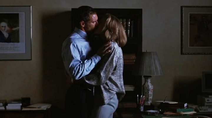 A man and a woman kiss in Presumed Innocence.