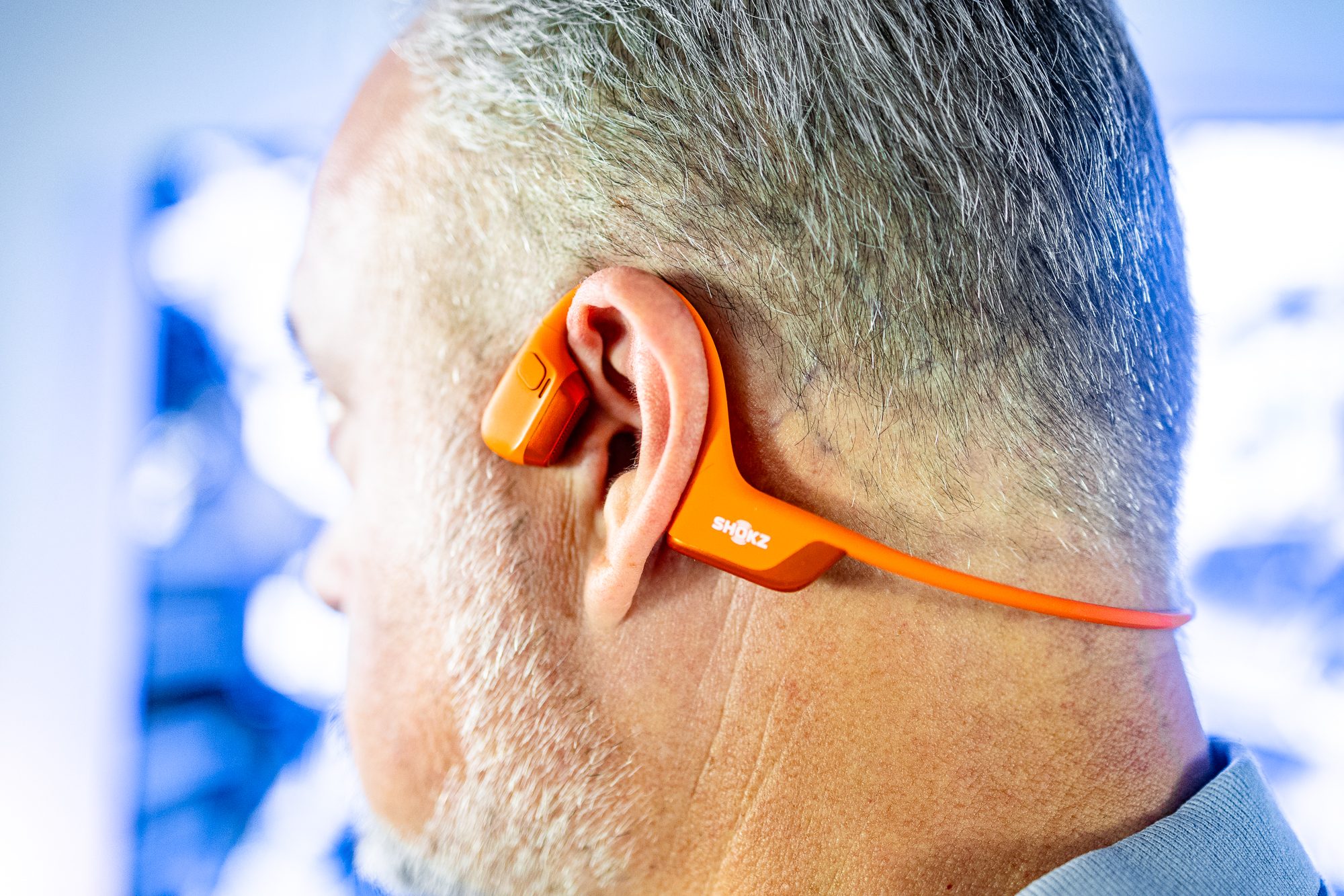 The Shokz OpenRun Pro 2 in orange as seen on the back of a large head.