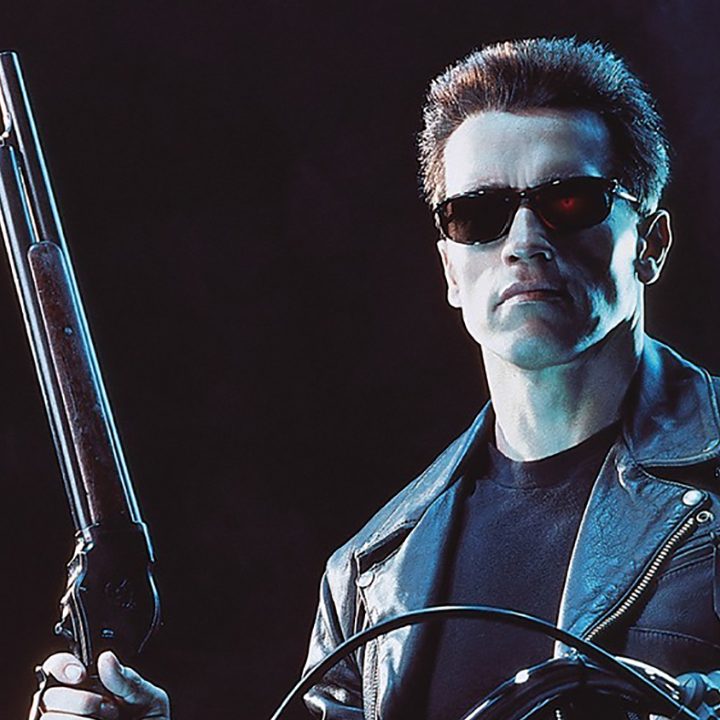Arnold Schwarzenegger with dark glasses holding a rifle in a scene from "Terminator 2: Judgement Day."