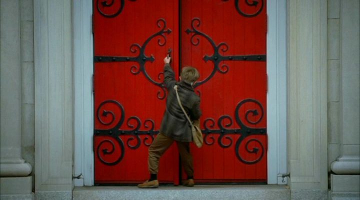 A boy knocks on a red door in The Sixth Sense.